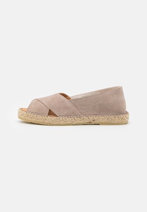 Beige suede espadrille with cross straps and open toe design. Jute-wrapped sole, flat heel, and smooth texture.