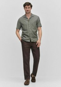 Olijfgroene overhemd met korte mouwen en een button-down kraag, gecombineerd met bruine linnen broek en bruine instap schoenen. Gladde textuur, casual ontwerp.
