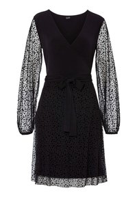 Svart klänning med V-ringning och långa genomskinliga ärmar. Kjolen har ett prickigt mönster. Inkluderar en knytkrage för formning.