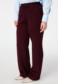 Bordeaux joggers van zacht materiaal, voorzien van een elastische tailleband met koord, zijzakken en rechte, losse pijpen.
