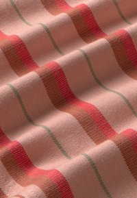 Gestreepte textiel in zacht roze, met golvende lijnen in rood, bruin en groen. De stof heeft een gladde textuur met een zichtbaar weefpatroon.