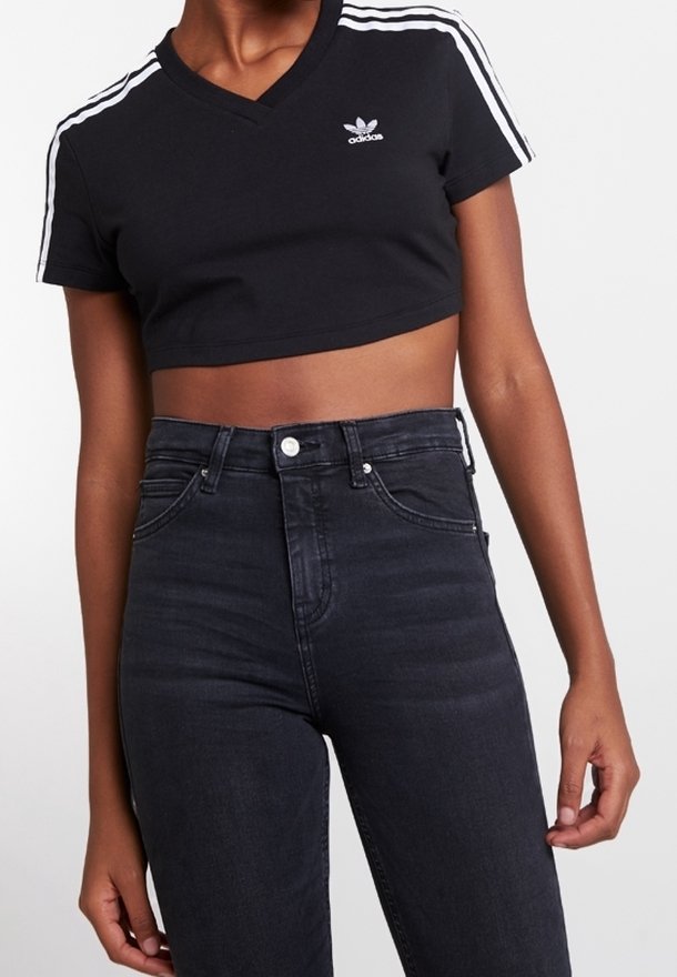 Černé zkrácené tričko s výstřihem do V, na ramenou zdobené třemi bílými pruhy a malým bílým logem. V kombinaci s tmavými džínami s vysokým pasem.
