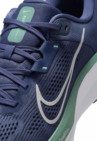 Scarpa da corsa da uomo con tomaia in rete blu navy, logo swoosh bianco, accenti verdi, superficie testurizzata e suola ammortizzata con ritagli.