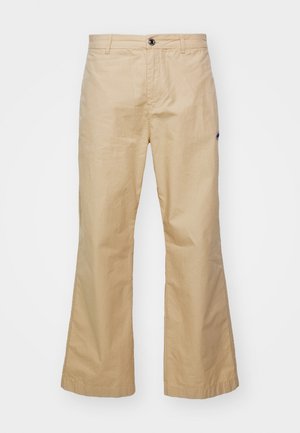 Beige flared trousers made of smooth fabric. Features front pockets, a button closure, and subtle textured stripes.