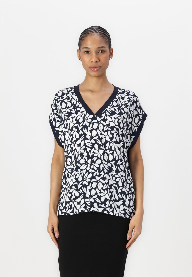 Marineblaues V-Ausschnitt-Bluse mit weißem Blattmuster. Kurze Ärmel, leichtes Material und eine lockere Passform mit abgerundetem Saum.