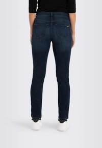 Kapeakka tummansiniset farkut, joissa on korkea vyötärö, kahdella takataskulla ja hienovaraisella ompelulla. Yhdistettynä valkoisiin urheilukenkien kanssa.