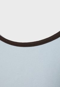 Tissu bleu clair avec gros plan sur la couture côtelée marron foncé au niveau de l'encolure d'un vêtement.