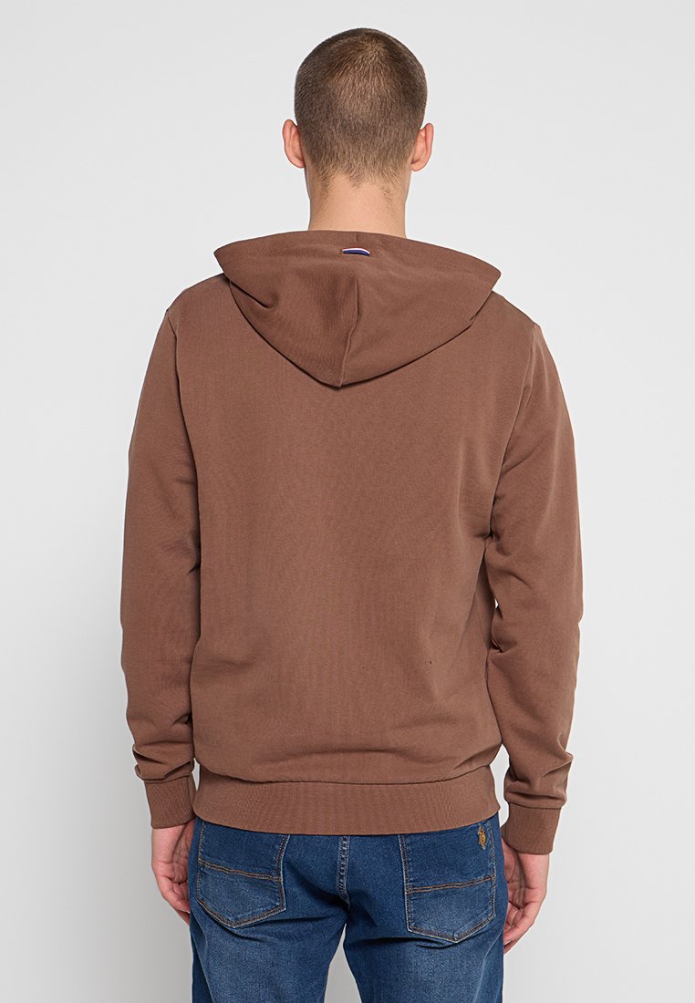 Sudadera marrón con capucha, hecha de una tela suave. Presenta puños y dobladillo de canalé, y un pequeño logo en la parte posterior.