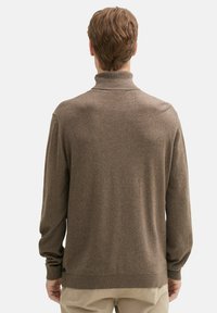 Brązowy sweter z wysokim kołnierzem, długimi rękawami i prążkowanymi mankietami. Wykonany z miękkiego materiału, o gładkiej fakturze i minimalistycznym wzornictwie.