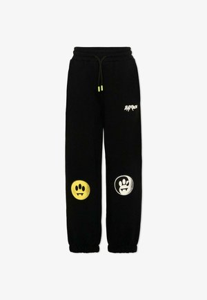 Pantalon de survêtement noir avec poignets et taille élastiques, présentant des empreintes de pattes circulaires jaunes et blanches sur les genoux et un logo blanc sur la cuisse supérieure.