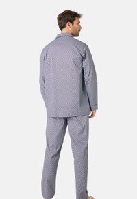 Ensemble de pyjama pour hommes en navy et blanc à pois, comprenant une chemise à col et un pantalon assorti, fabriqué en tissu doux et respirant pour le confort.