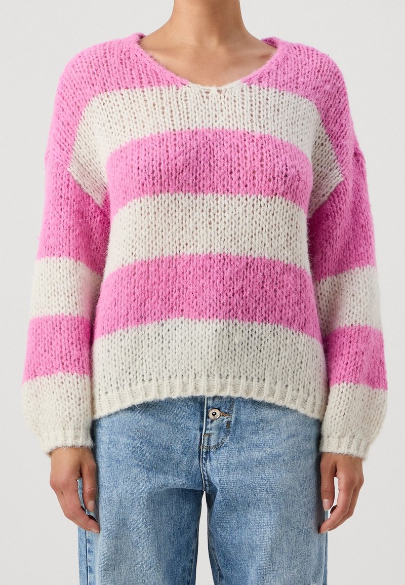 Pull en maille rayé rose et blanc avec col en V, coupe ample et poignets côtelés ; texture douce et duveteuse avec manches larges.