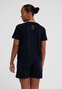 Black athletic t-shirt with short sleeves, featuring a round neckline and three arrow-shaped white accents on the upper back. Suitable for sports.