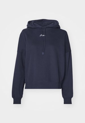 Navy bluehuppari, joka on valmistettu pehmeästä kankaasta, jossa on kiristettävä huppu ja brodeerattu logo rinnassa. Rentoa istuvuutta ja ribbaettu hihansuut.