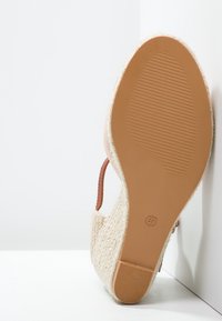 Open-toe shoe featuring a textured, woven upper in beige, a brown leather strap, and a flexible rubber sole with a grip pattern. Size 37.
