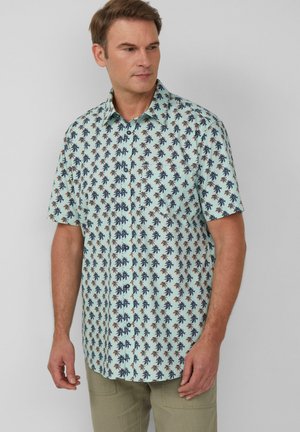 Chemise à manches courtes à boutons en bleu clair avec un motif de palmiers tropicaux. Fabriquée en tissu lisse, elle présente un col classique et des boutons sur le devant.