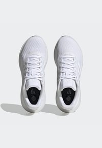 White athletic shoes featuring a textured upper, round toe, lace closure, and eco-friendly lining text with a globe graphic.