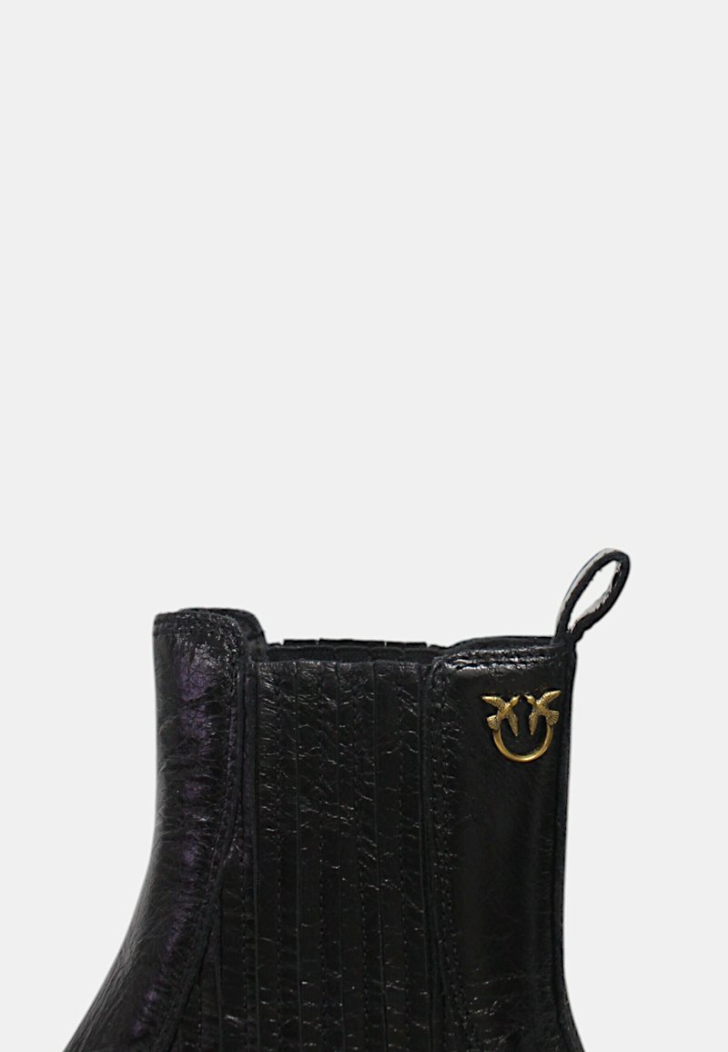 Czarny botek za kostkę z teksturowanym wykończeniem z sztucznej skóry, z pionowymi żłobieniami i złotym logo akcentującym u góry.