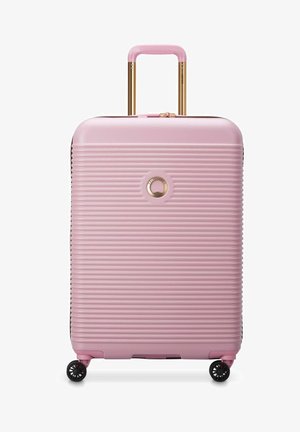 Valigia rigida rosa con scanalature verticali, accessori in oro, manico estensibile e quattro ruote girevoli nere per una facile manovrabilità.