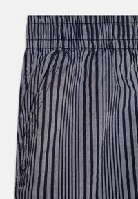 Stripet stoff i marineblått og lys grått, med en rynket midje og sidelomme. Materialet virker lett og teksturert.