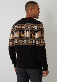 Ciemnobrązowy sweter dzianinowy z kolorowym zimowym wzorem przedstawiającym drzewa, renifery i płatki śniegu w odcieniach kremowym, pomarańczowym i białym.