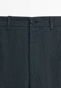 Dark denim trousers with a visible waistband, belt loops, and a single black button closure at the front.