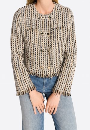Chaqueta de tweed tejida en color crema con cuadros oscuros, con un dobladillo y puños con flecos, botones dorados de doble botonadura y bolsillos laterales.