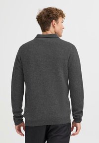 Suéter de punto gris carbón con cuello, mangas largas, puños acanalados y dobladillo inferior. Textura suave con un acabado liso.