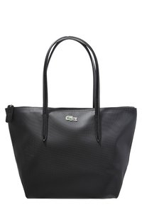 Sac fourre-tout noir avec une surface texturée, deux anses d'épaule et un petit logo crocodile vert sur le devant. Compartiment zippé visible.