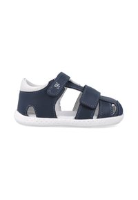 Sandalia de cuero azul marino con diseño abierto, acentos blancos, dos correas ajustables de Velcro y una suela blanca texturada con pequeños puntos.