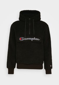 Schwarze Sherpa-Hoodie mit halbem Reißverschluss vorne, Kordelzügen, Champion-Logo auf der Brust und kleinem Logo am Ärmelsaum links.