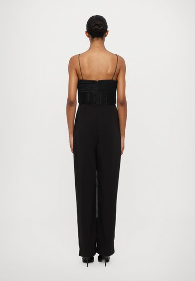 Zwarte jumpsuit met dunne bandjes en een geplooide bovenkant. Beschikt over brede pijpen en een rechte snit, ontworpen met minimale details en een gladde textuur.