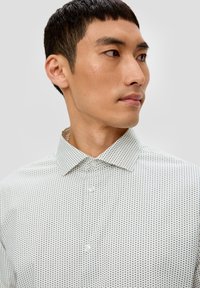 weißes Hemd mit kleinem Dreiecksdesign in Dunkelblau, mit Button-Down-Kragen und transparenten Knöpfen. Glatte Stoffstruktur.