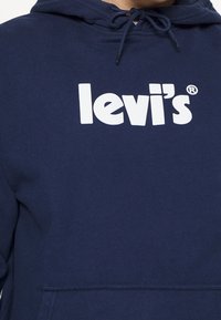 Námořnická modrá mikina s kapucí vyrobená z bavlněné směsi, s velkým bílým logem "levi's" přes hrudník a přední klokaní kapsou.