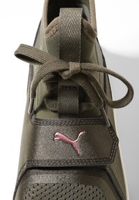 Green athletic shoe with a smooth, textured finish, mesh panels, and a pink Puma logo. Features a lace-up design and padded tongue.