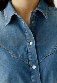 Jeanshemden met een button-down kraag, lichtblauwe kleur, zichtbare stiksels, drukknoopsluitingen en een yoke-detail in westerse stijl.