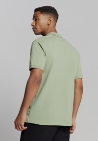 Korte mouwen polo shirt van lichtgroene katoenstof, met een klassieke kraag en zonder zichtbare patronen, weergegeven vanuit de achterkant.