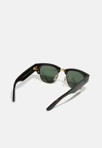 Ochelari de soare negri în stil cat-eye cu lentile verzi, accente din metal auriu și un finisaj lucios. Punctează cu tampoane pentru nas detașabile pentru confort.