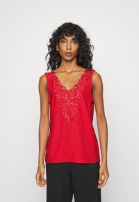 Top vermelho sem mangas com um decote em V profundo e um intricado bordado na gola. Tecido suave, ajuste descontraído.