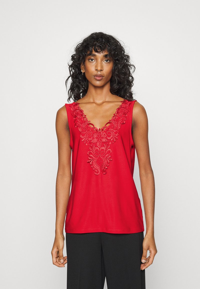 Top vermelho sem mangas com um decote em V profundo e um intricado bordado na gola. Tecido suave, ajuste descontraído.