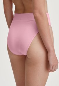 Sous-vêtements en coton rose à taille haute, avec une texture douce et un design sans coutures, présentant une large ceinture et une finition lisse.
