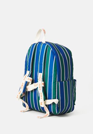 Mochila a rayas azules y verdes con correas blancas, cuerpo acolchado y un asa en la parte superior. Cuenta con dos bolsillos laterales y un cierre de cremallera.