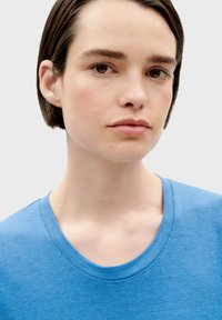 Blaues Baumwoll-T-Shirt mit rundem Halsausschnitt, glatter Textur und kurzen Ärmeln, auf einem neutralen Hintergrund präsentiert.