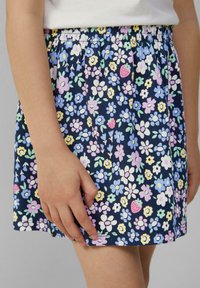 Bloemenrok van zacht materiaal, met een marineblauwe achtergrond en kleine roze, paarse en groene bloemen, en een elastische tailleband voor extra comfort.