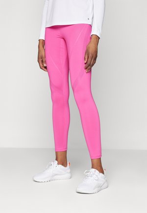 Tette rosa leggings med teksturerte detaljer og sømmer, kombinert med hvite joggesko. Materialet ser elastisk og glatt ut.