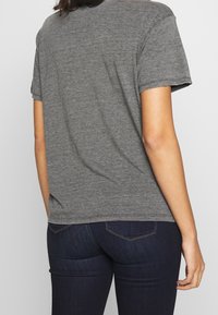 Szara koszulka z krótkim rękawem i okrągłym dekoltem, wykonana z miękkiego materiału. Tył jest gładki, bez widocznych wzorów ani akcentów.