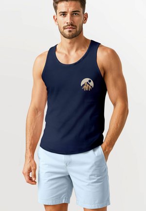 Navy blue tank top with a round neckline and a printed mountain and sun design in beige. Paired with light blue shorts.