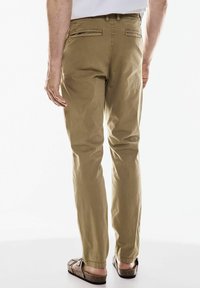 Ljust bruna bomullsshorts med en avspänd passform, som har två bakfickor och elastiska muddar, i kombination med platta sandaler.