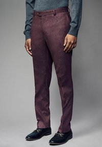 Bordeauxfarbene Wollhosen mit texturiertem Finish, flacher Front, Seitentaschen und einem einzigen Knopfverschluss. Kombiniert mit schwarzen Slippern.