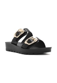Chanclas negras con dos correas ajustables, que cuentan con hebillas metálicas doradas y una suela de cuña gruesa y texturizada.